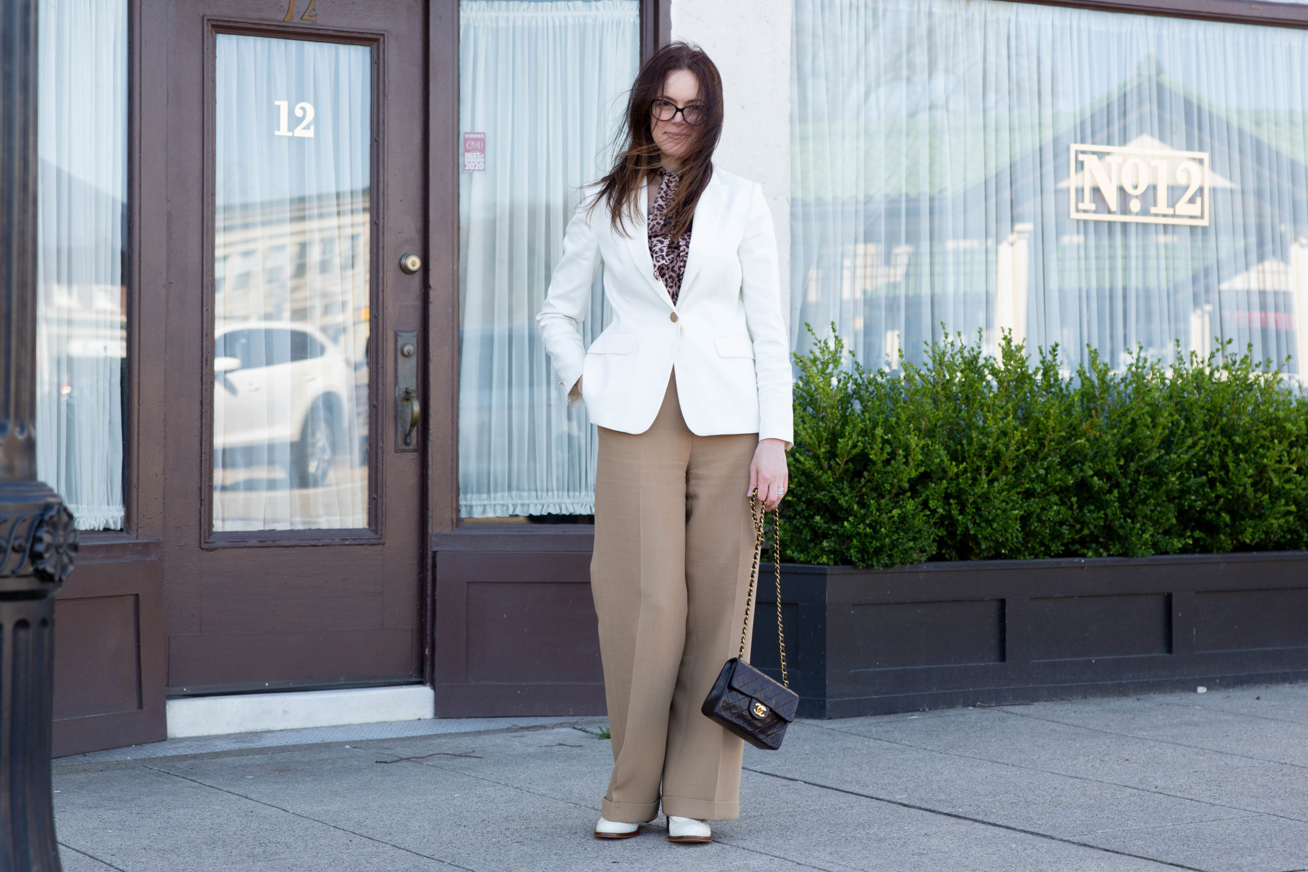 michelle wears white blazer, secondhand camel pants and shoes. vintage chanel bag with leopard print tie neck rixo blouse, is she a fashion influencer?